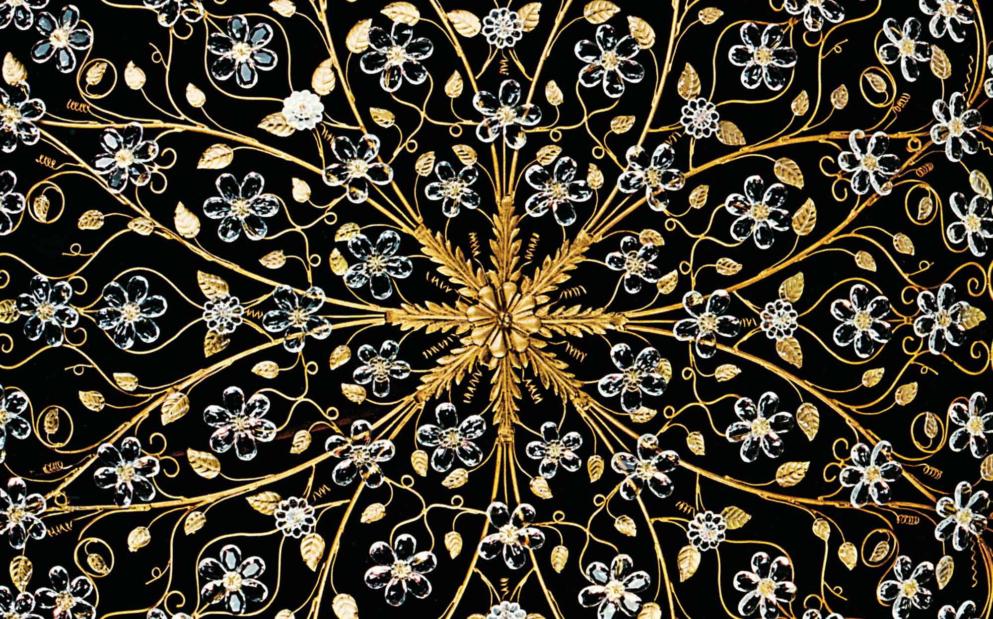 G. Moscatelli Luxury Crystal Chandelier Detail | 101domus Ornate luxury crystal chandelier detail by G. Moscatelli with gold decorative structure and floral crystal elements, classic Italian ceiling lighting design.