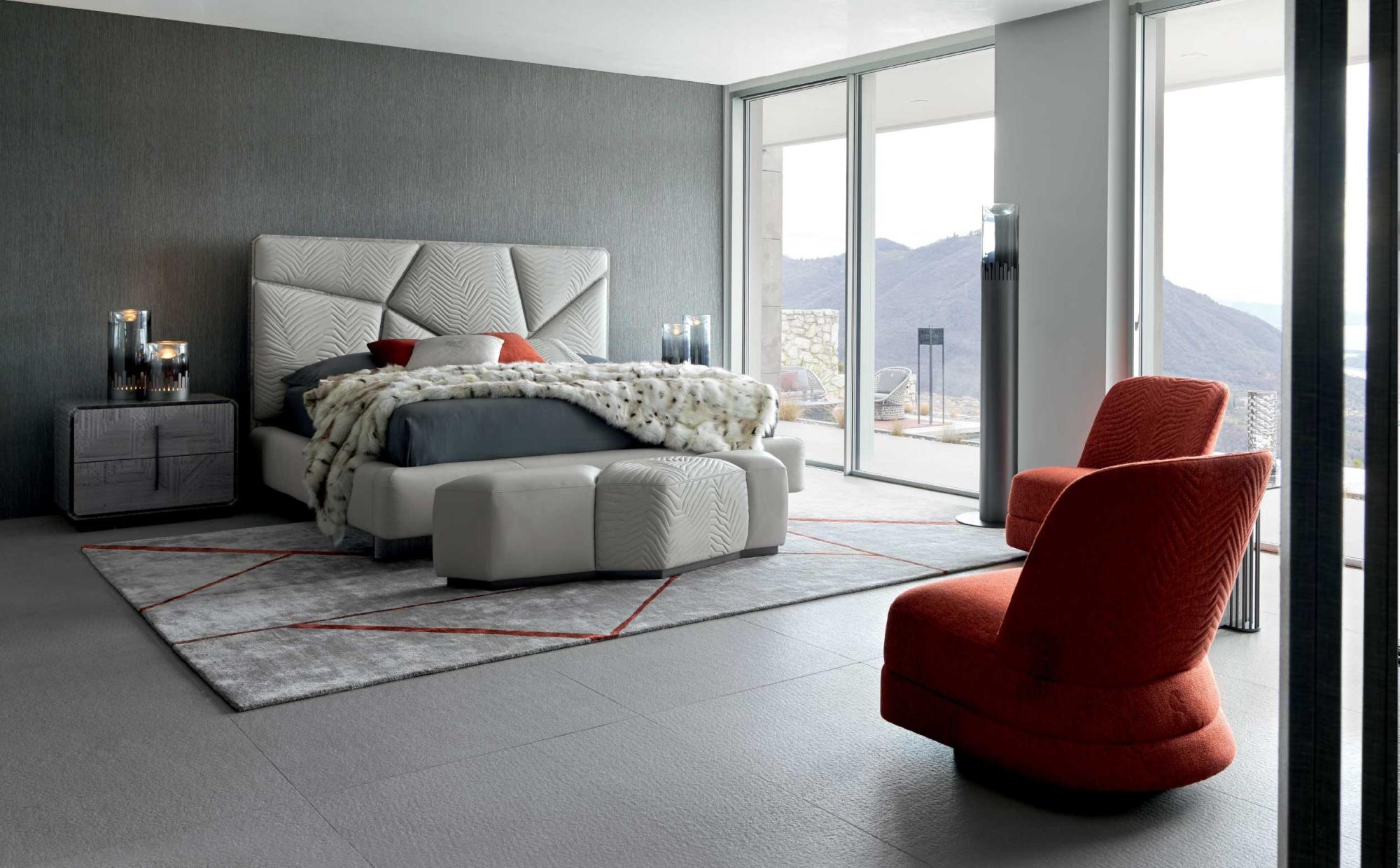 Bedroom with upholstered bed and contemporary red armchairs | 101DOMUS Modern bedroom with quilted headboard, red armchairs and panoramic view