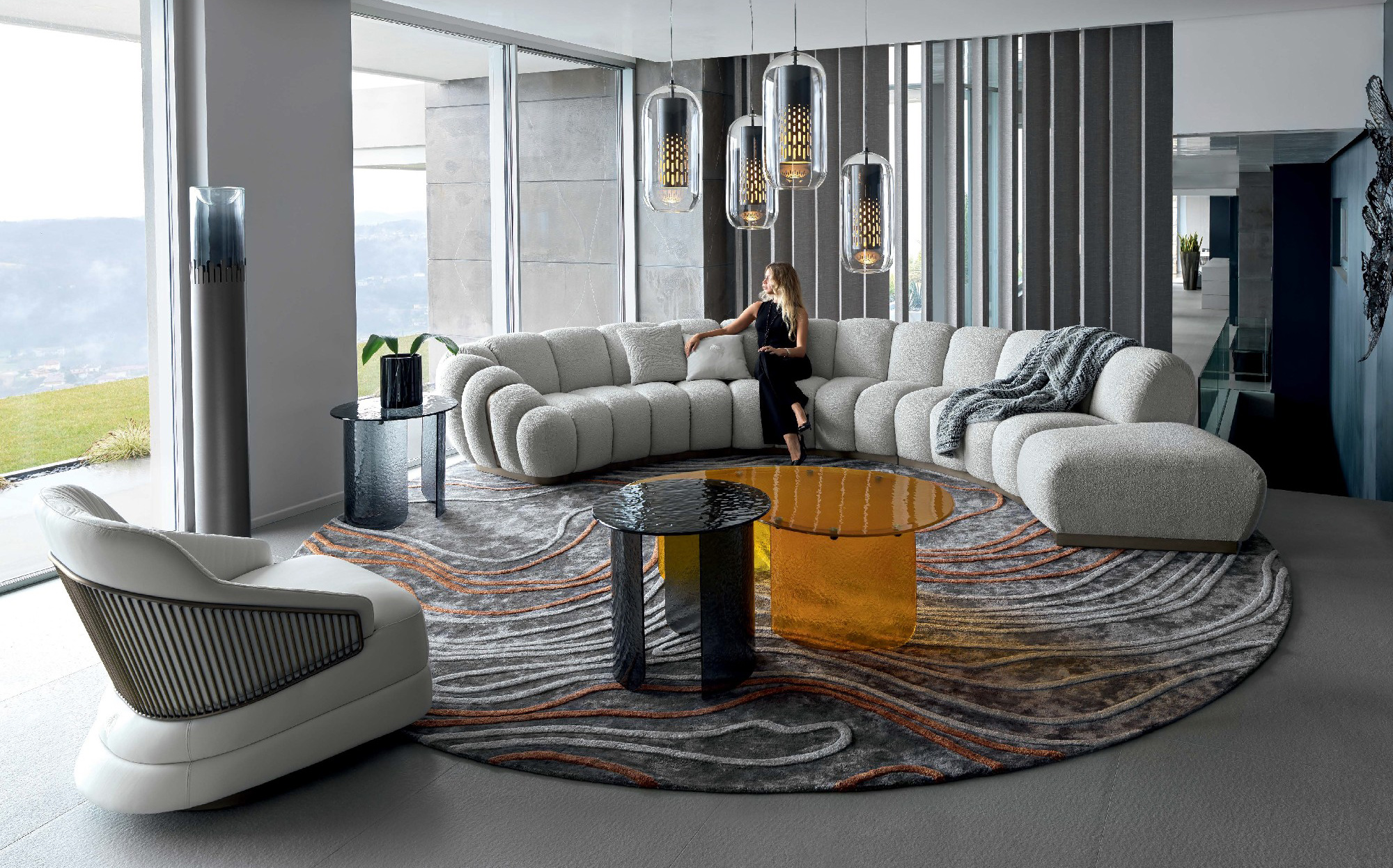 Designer living space with curved sofa and contemporary accents | 101DOMUS Modern living room with grey modular sofa, round rug, and colorful coffee tables