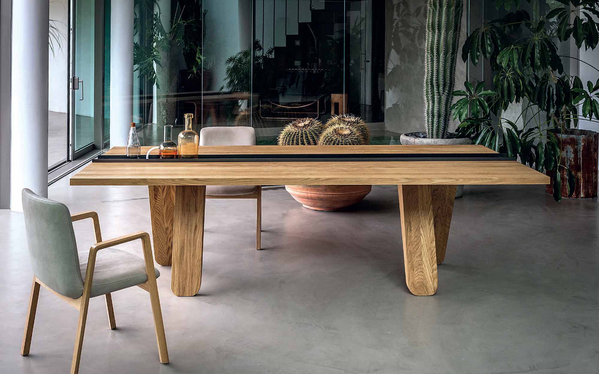 Large solid wood dining table in modern space with natural light and plants &ndash; Riva1920