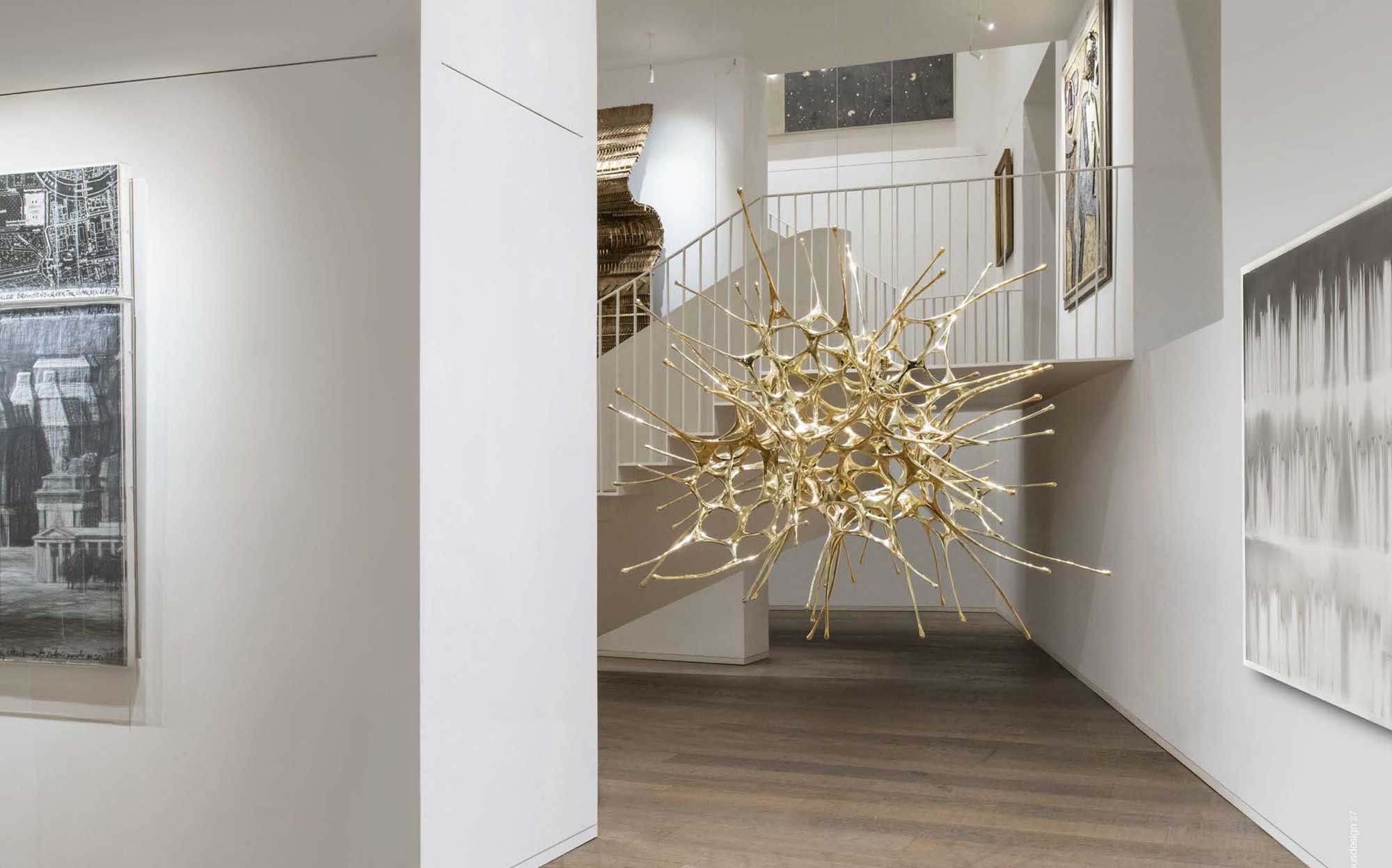 Sculptural gold-finish suspension lamp by Terzani for designer interiors | 101DOMUS Golden artistic suspension by Terzani with sculptural organic structure in a modern exhibition space