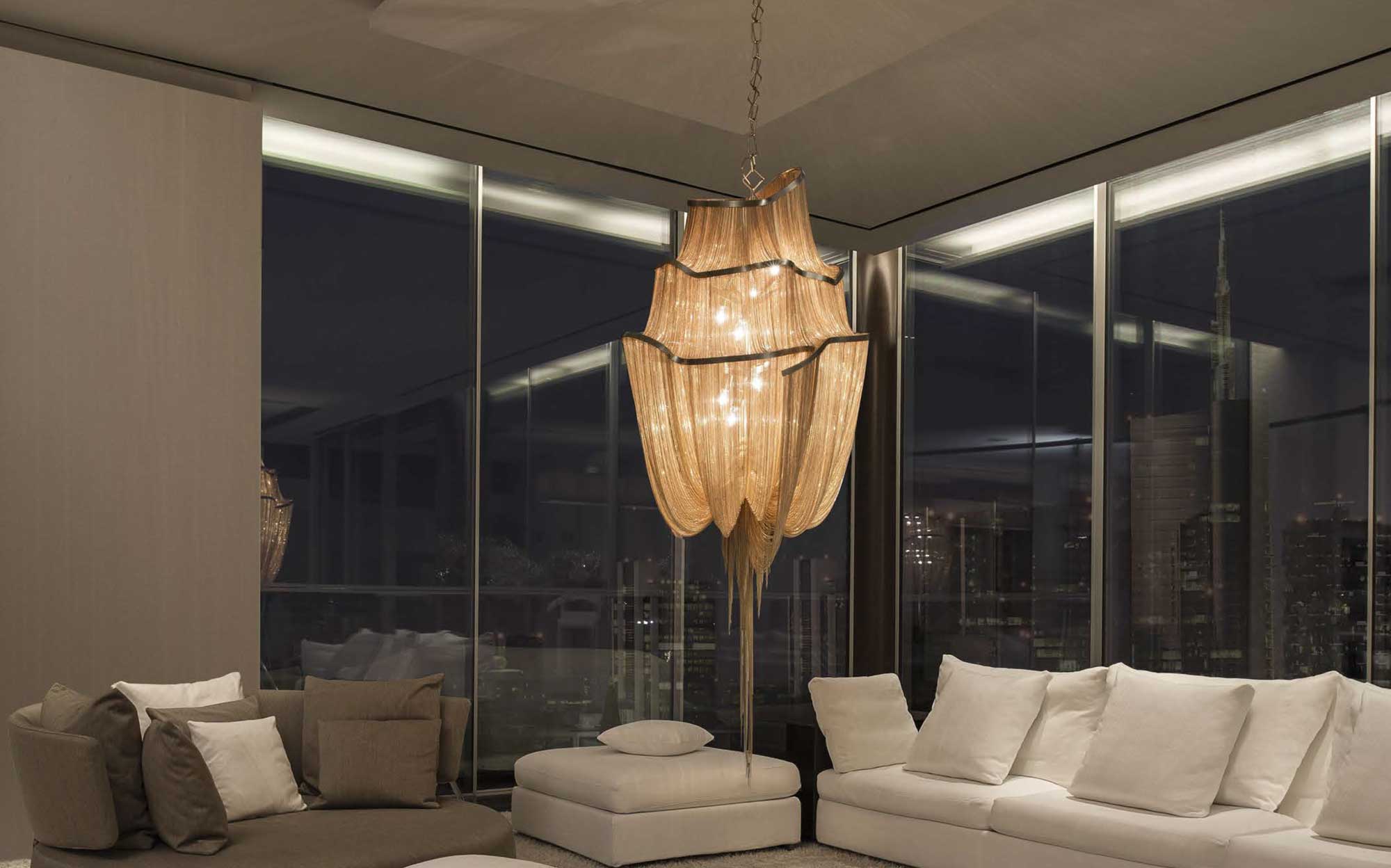 Designer Terzani chandelier with golden chains for a luxury living room with panoramic view | 101DOMUS Majestic Terzani chandelier with luminous chains in a modern living room overlooking the city at night