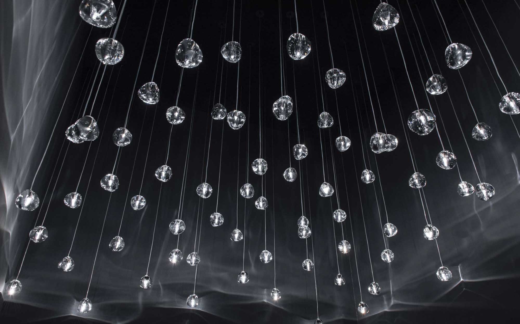 Terzani crystal drop installation: luminous elegance for exclusive spaces | 101DOMUS Terzani lighting installation with suspended crystal drops on a dark background