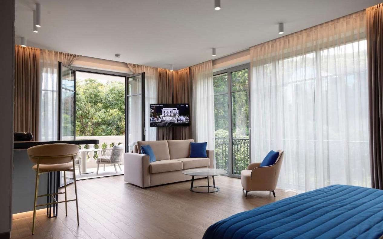 Suite with sofa, armchair, bar stools and garden-facing windows, Boutique Hotel Stresa on Lake Maggiore | 101domus