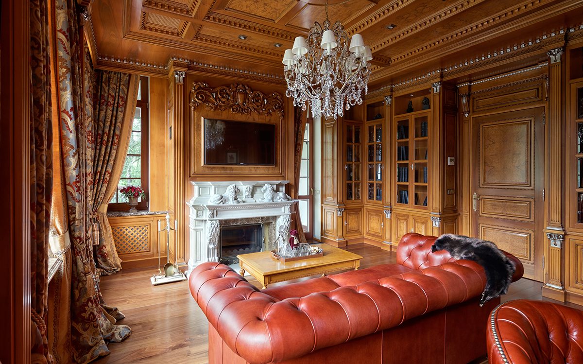 Library with carved fireplace, wooden bookcases and red leather sofa, Francesco Molon classic villa | 101domus