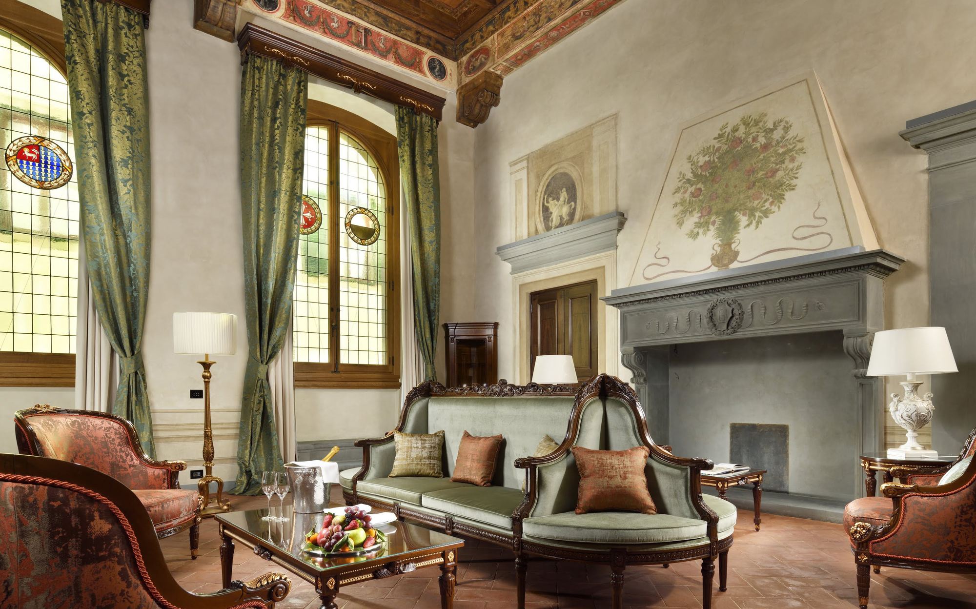 Salon with stone fireplace, green sofa and carved armchairs, Palazzo Portinari Salviati Florence | 101domus