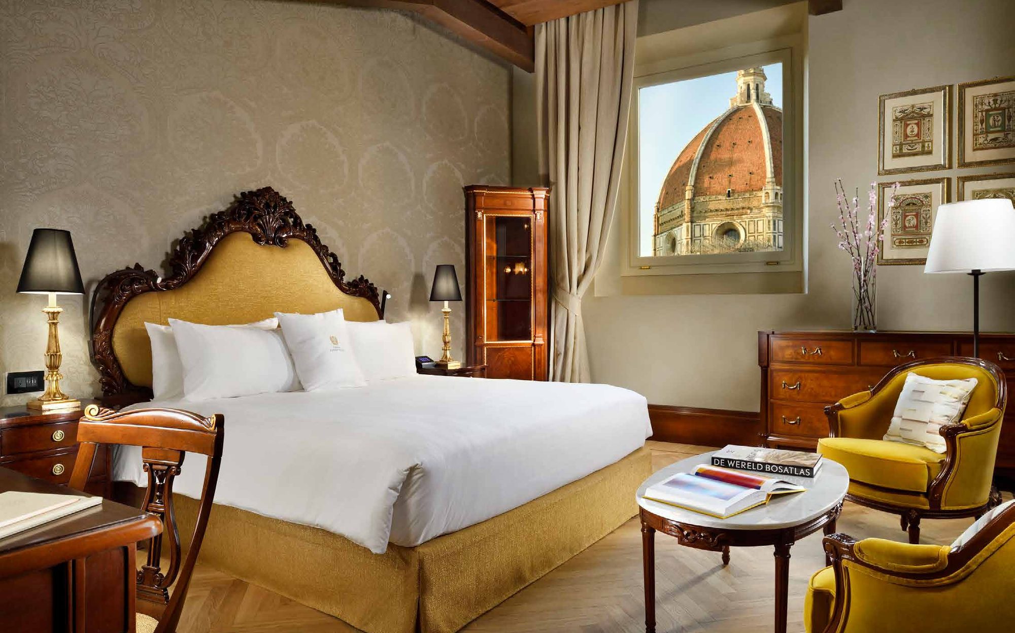 Bedroom with carved headboard, yellow armchairs and Duomo view, Palazzo Portinari Salviati Florence | 101domus
