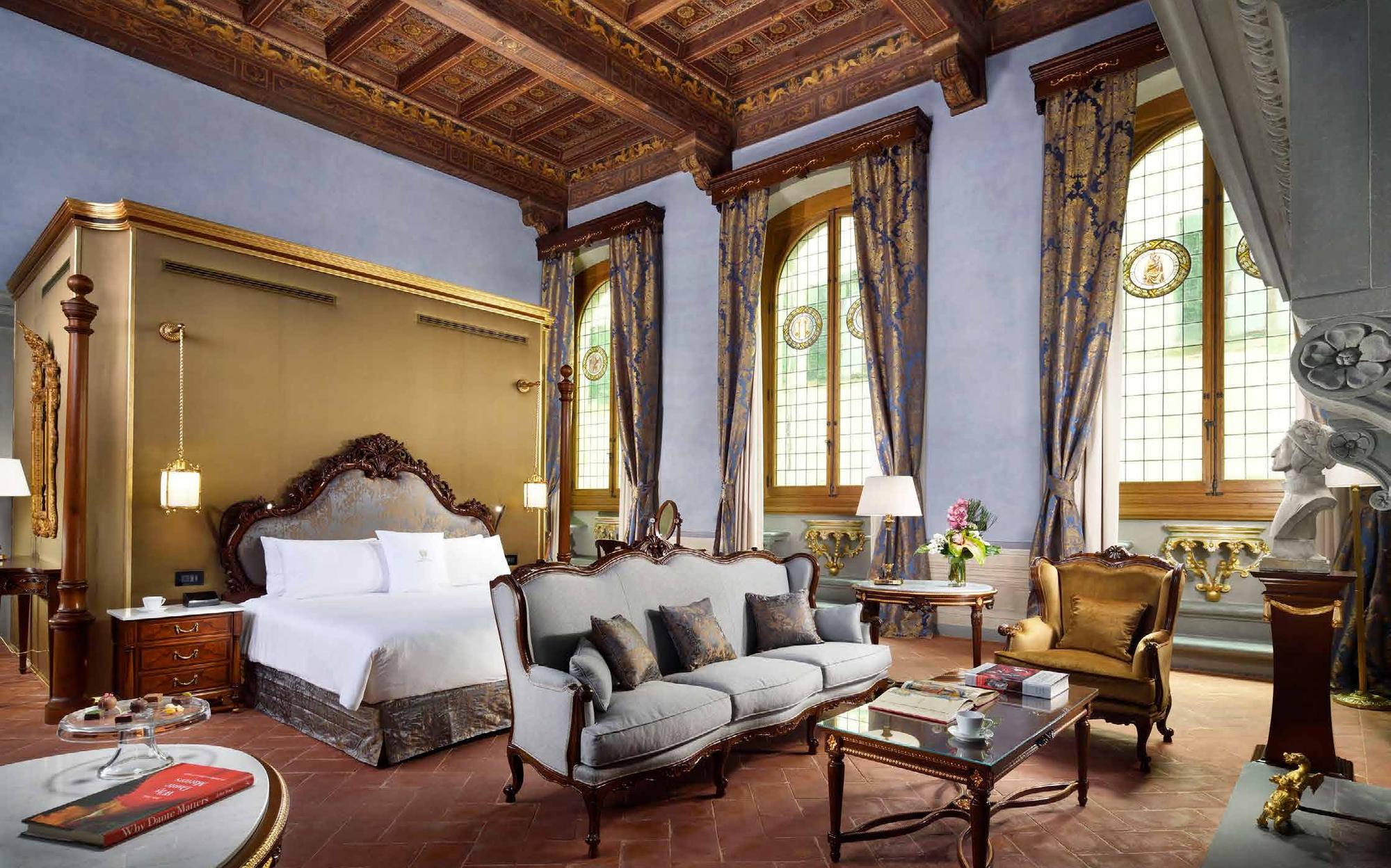 Bedroom with gilded headboard wall and grey sofa under a coffered ceiling, Francesco Molon in Florence | 101domus