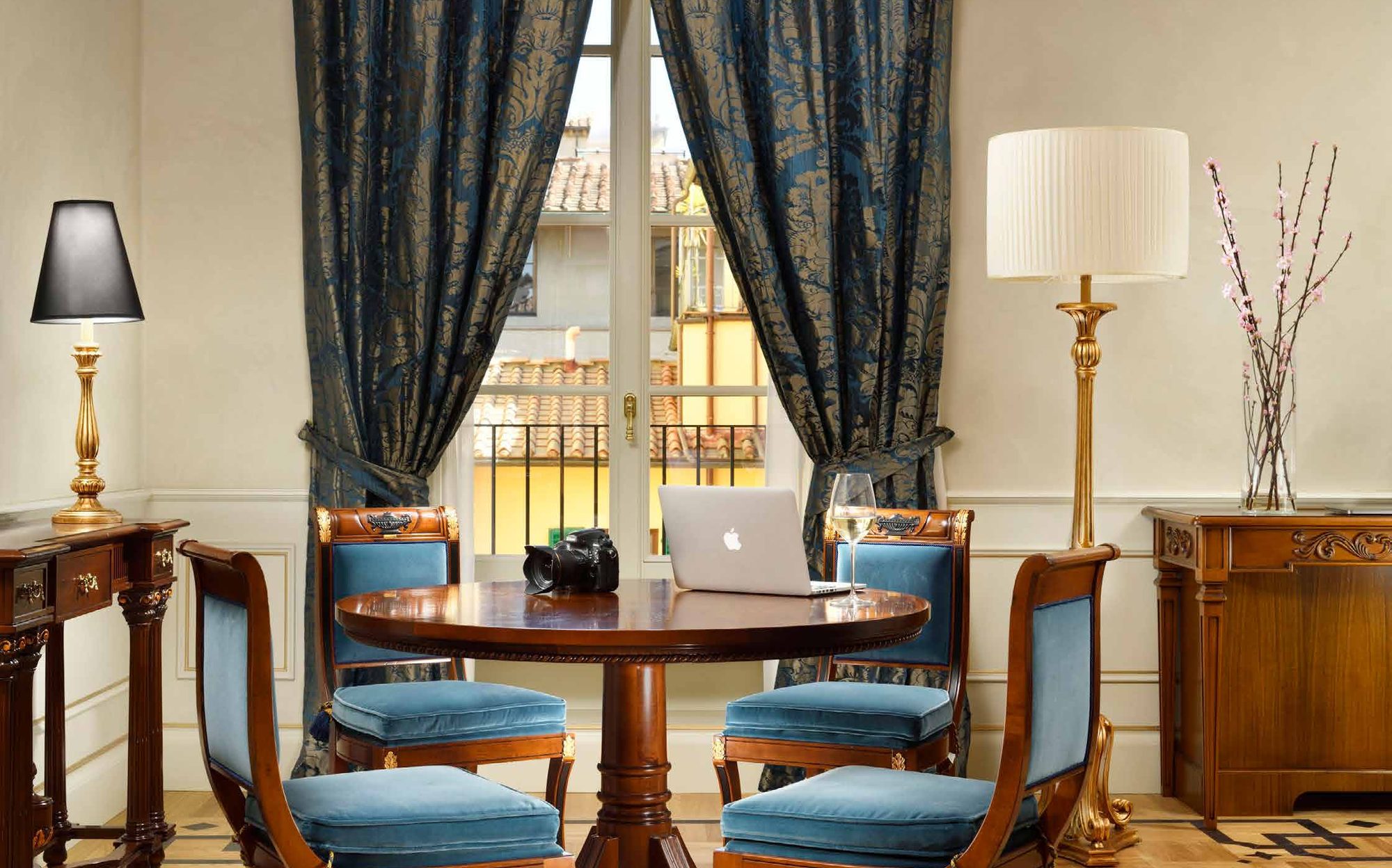 Round dining table with blue upholstered chairs in a suite of Palazzo Portinari Salviati, Florence | 101domus