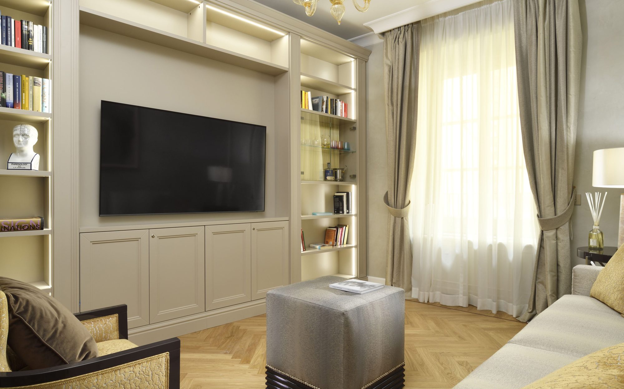 Contemporary apartment living room with fitted bookcases and TV wall, Palazzo Portinari Salviati Florence | 101domus
