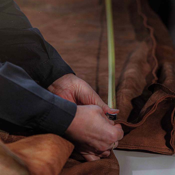 Craftsmanship detail &ndash; hands measuring fine leather in Italian upholstery atelier | 101DOMUS